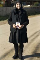 Old woman dressed in black with a prayer book, returning from church, Botiza, Maramures, Romania